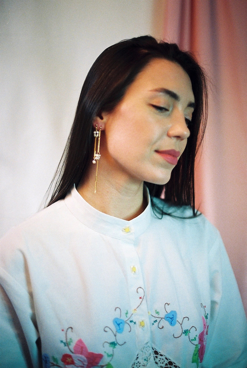 Boucles d'oreilles upcyclées ornées de perles d'eau douce et de chaînes en plaqué or portées par une femme de profil. 